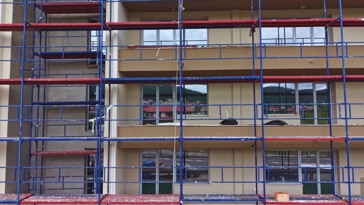 Bygningsrenovering er i gang. Facaderenovering med stilladser og arbejdere til stede. Renoveringsarbejde på lejlighedens ydre med flere arbejdere til stede.