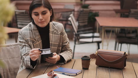 Young-businesswoman-making-online-payment-on-smartphone-during-coffee-break.