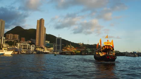 shot of a chinese boat passing by in a city environment near a coast city during the end of the afternoon