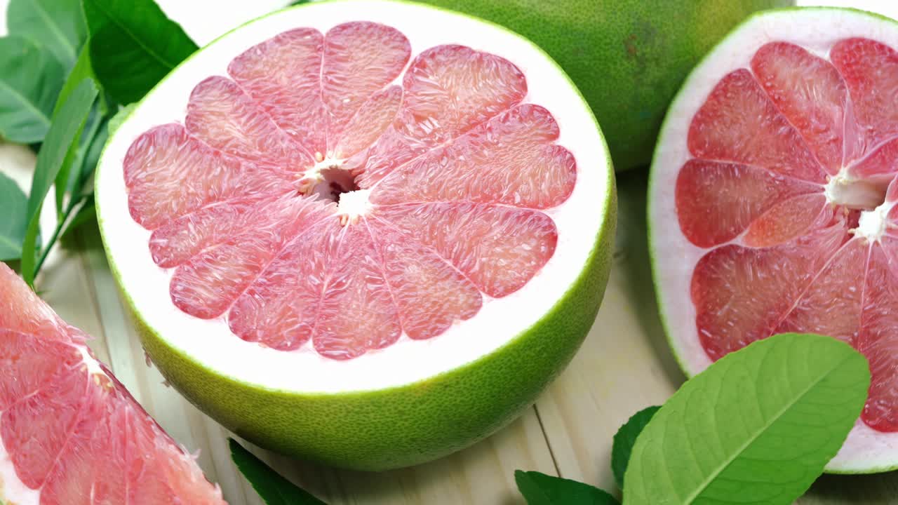 정원에서 나무 테이블에 잎을 가진 빨간 포멜로 과일을 회전, 나무 배경 4k 해상도에서 잎과 함께 빨간 포মেল로 과일.