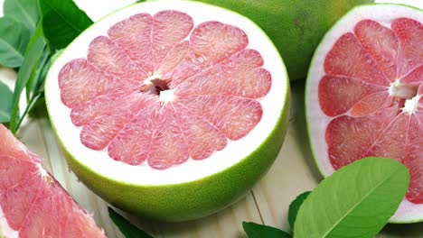 vista superior girar la fruta de pomelo roja con hojas en la mesa de madera en el jardín, la fruta del pomelo rojo con hojas con fondo de madera resolución 4k.