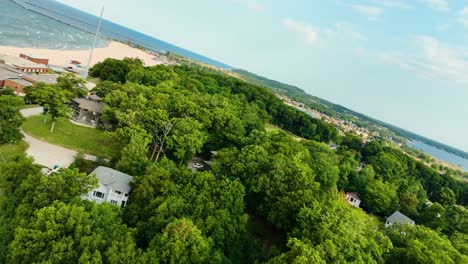 Flight-view-turn-over-lush-trees-in-Muskegon,-MI