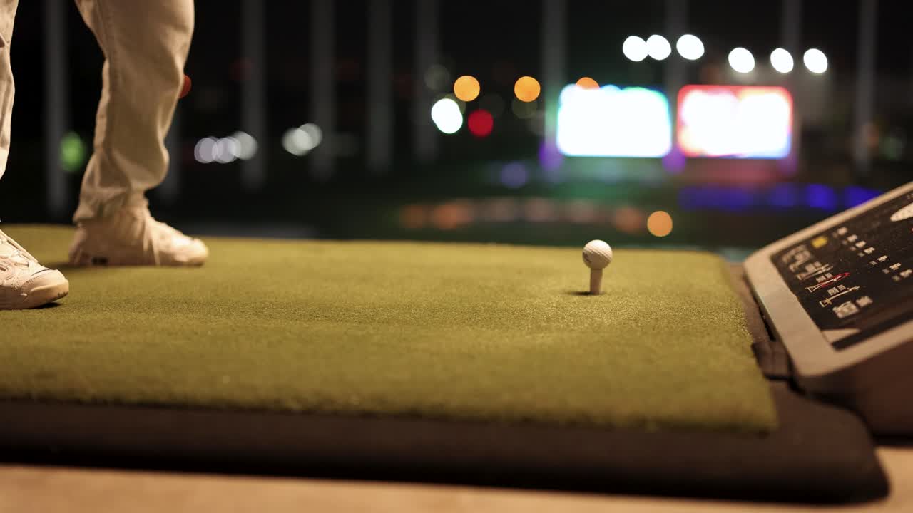 Golfista che pratica lo swing in un driving range notturno