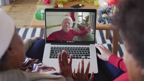 Madre-E-Hija-Afroamericanas-Usando-Una-Computadora-Portátil-Para-Una-Videollamada-Navideña-Con-Un-Hombre-En-La-Pantalla