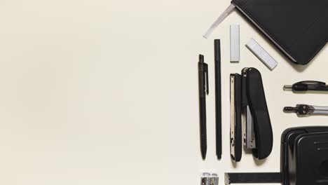 stop motion of monochrome office supplies sliding in and arranging, leaving big negative space