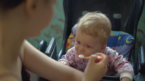 mother feeds child with porridge