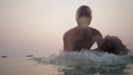 couple embracing in the ocean at sunset