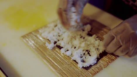 Person-Spreading-Rice-Over-Green-Paper-Preparing-Sushi-Roll,-Homemade