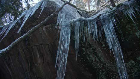 Huge-frozen-icicle-over-a-rocky-mountain-in-winter-forest