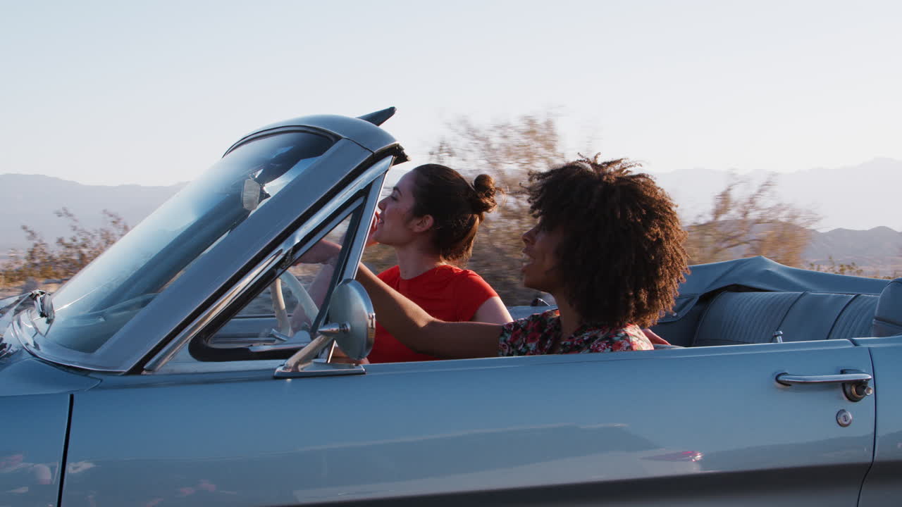 dos amigas apuntando desde un coche convertible