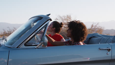 Two-female-friends-pointing-from-a--convertible-car