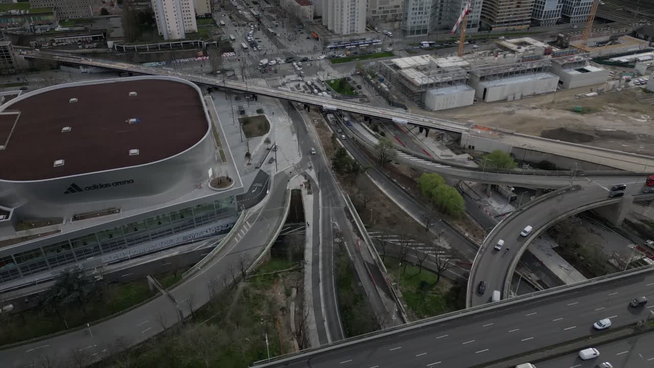 Adidas Arena, Porte de la Chapelle, busy highway interchange with cars, modern buildings, and urban development in Paris, France. Aerial drone view