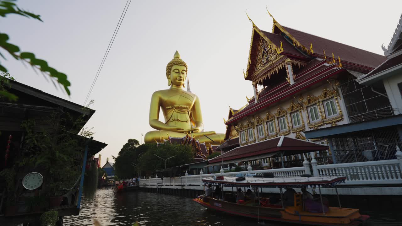 Tourist Boat in Bangkok Thailand floats by in front of the temple with a golden buddha statue