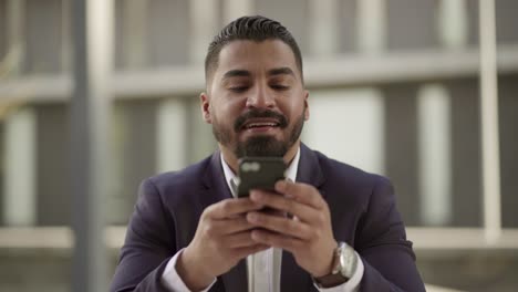Hombre-Sonriente-Usando-Teléfono-Celular-Al-Aire-Libre