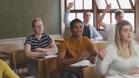 student raising his hand in high school class