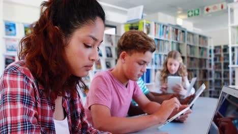 Aufmerksame-Schulkinder-Nutzen-Laptop-Und-Digitales-Tablet-In-Der-Bibliothek