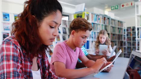niños de escuela atentos usando computadora portátil y tableta digital en la biblioteca
