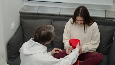 young woman receiving a gift from her husband for valentine's day