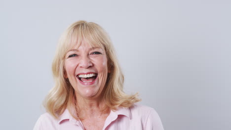 Foto-De-Estudio-De-Una-Mujer-Madura-Contra-Un-Fondo-Blanco-Riéndose-De-La-Cámara