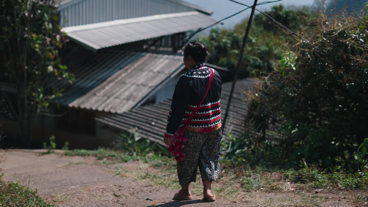 A woman in traditional clothing walking through a village