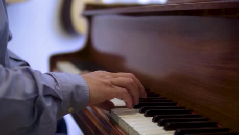 vista lateral de un músico de piano de mediana edad interpretando su canción con camisa azul creativo fondo borroso cámara lenta