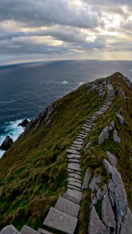stone steps winding up a rugged coastal cliff overlooking the ocean