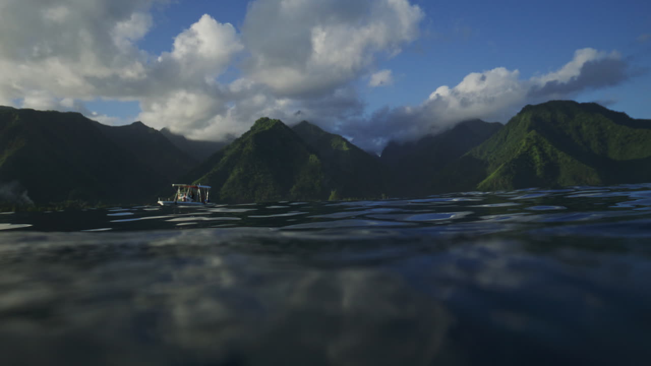 테아후푸 (teahupoo) 에서 서퍼들을 위한 지원 보트와 타히티 계곡의 산들을 바라보는 물