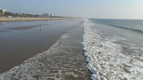 Olas-Rodando-En-La-Playa-En-Los-Anegeles-California,-Gente-Caminando-Por-La-Playa