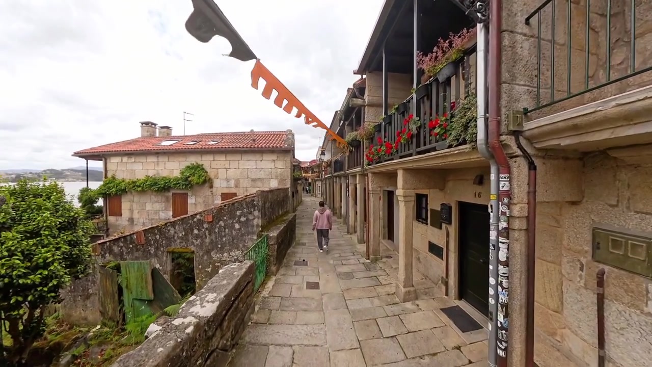 Pessoa caminhando pela histórica rua de paralelepípedos de Combarro, Pontevedra, Galiza, Espanha