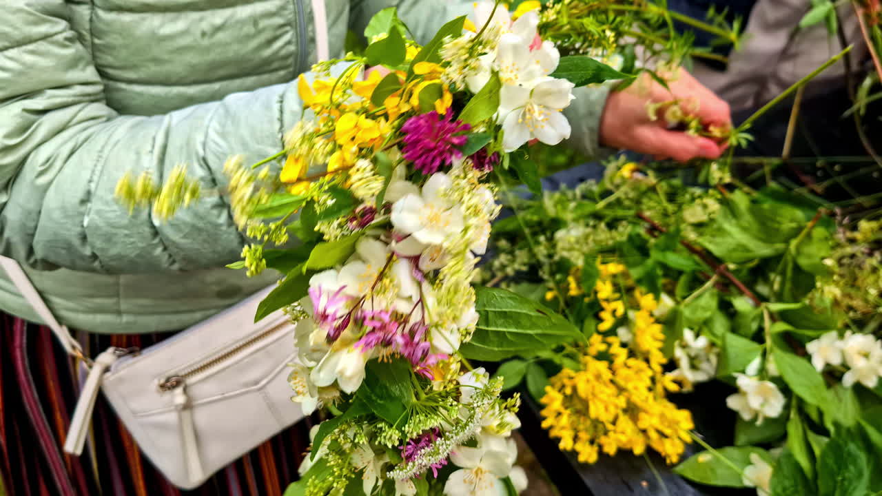 Donna che tiene in mano una ghirlanda di fiori fatta a mano con gelsomino, trifoglio e fiori gialli, solstizio d'estate.