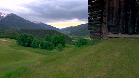 vista aérea que pasa por una cabaña rústica de madera con vistas al exuberante parque nacional high tauern, estado de salzburgo