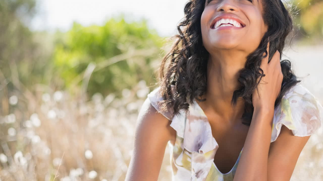 mujer biracial sonriendo con los ojos cerrados en un día soleado