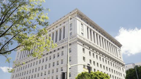 view onto the hall of justice in los angeles california during summer time with cars driving along - paning camera movement