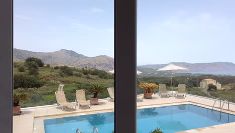 Close-Up-Interior-Shot-Looking-Outwards-towards-Pool---Sun-Loungers-with-Mountains---Ocean-in-Background