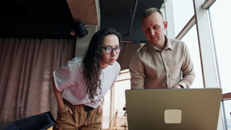 Caucasian people work in the office using laptop. Collaborative colleagues actively discuss the issue on the computer screen. Low angle view.