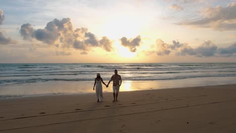 couple men and woman walking on the beach during sunset