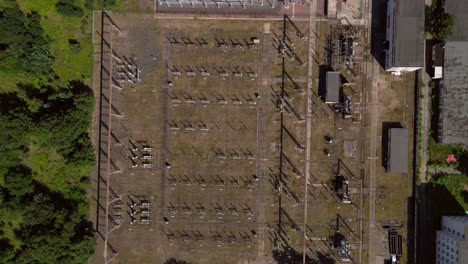 hennigsdorf substation, distributing electricity and surrounded by a lush green forest in brandenburg, germany. smooth aerial view flight vertical bird's eye view descending drone