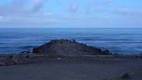 Vista-Lejana-De-Tres-Hombres-Pescando-En-El-Rompeolas,-Playa-Furadouro,-Portugal