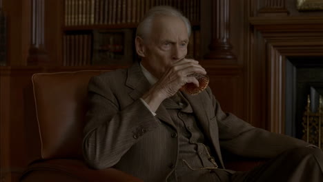 elderly gentleman sipping whiskey in a study