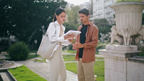 dos personas leyendo el contrato en el parque. socios latinas discutiendo papeles de informe