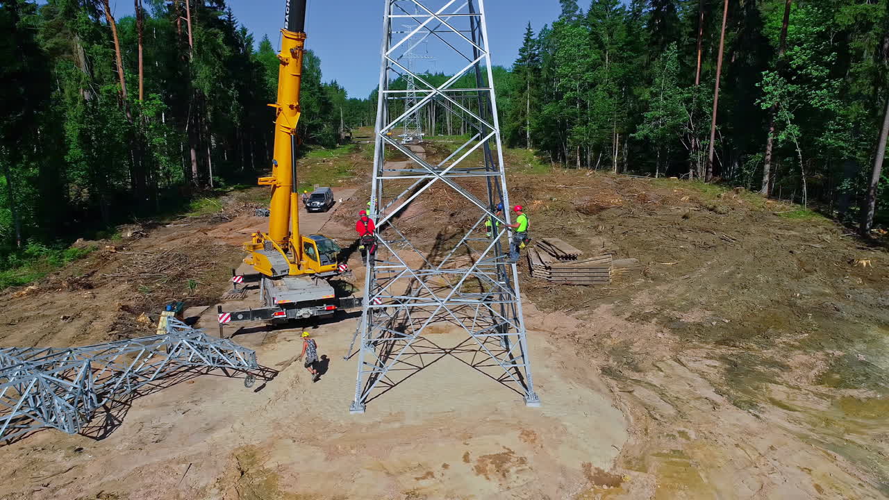 trabajadores instalando una torre de alto voltaje con grúa en el bosque