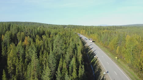 aerial follows tour bus on highway through flat northern boreal forest
