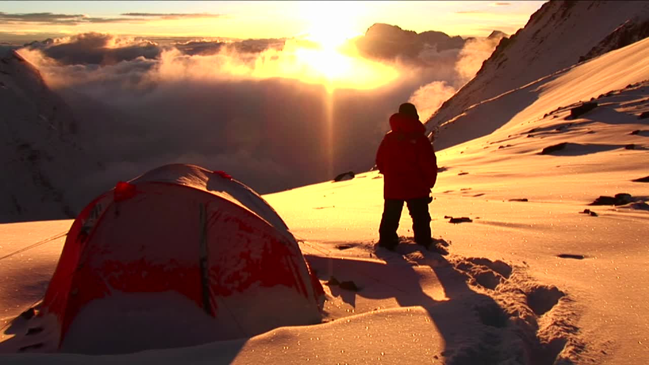 히트 텐트 밖에 서 있는 등반가