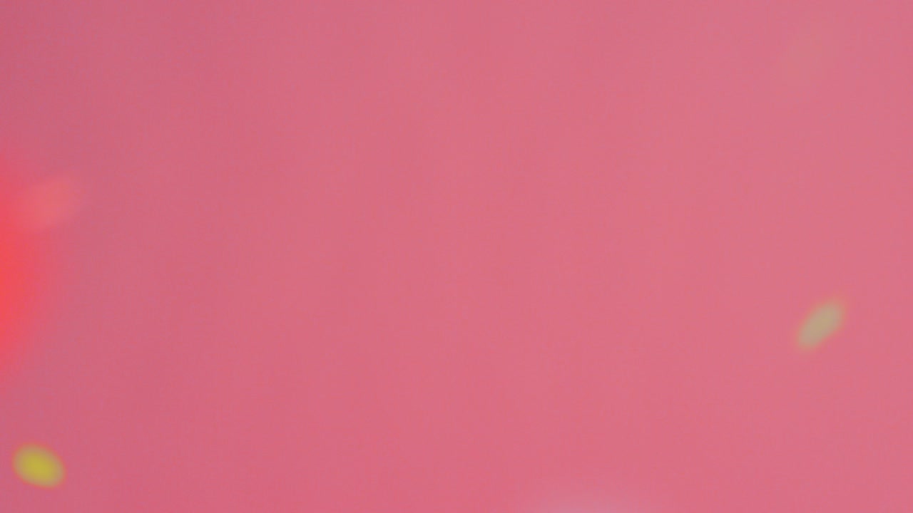 toma estacionaria de confeti dorado y de colores que cae sobre un fondo rosa brillante