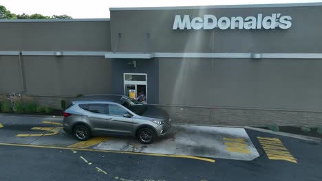 mcdonald's drive-thru. car at fast food pickup window. worker handing customer food. chain restaurant theme.
