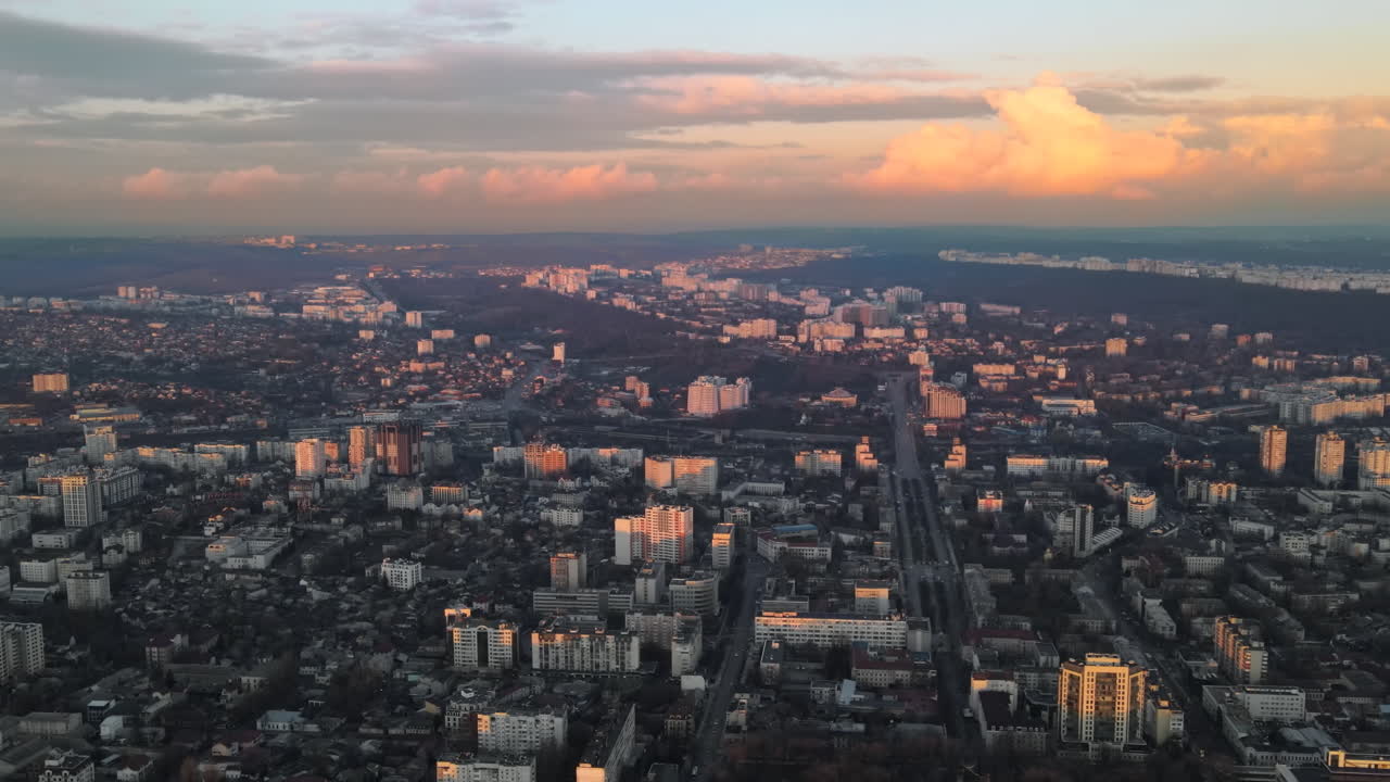 Aerial drone view of Chisinau at sunset. Panorama view of multiple buildings, roads with moving cars, bare trees. Moldova