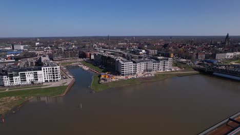 aerial view of noorderhaven neighbourhood in zutphen, the netherlands, seen from above and on the other side of the river ijssel with large cargo ship in the foreground