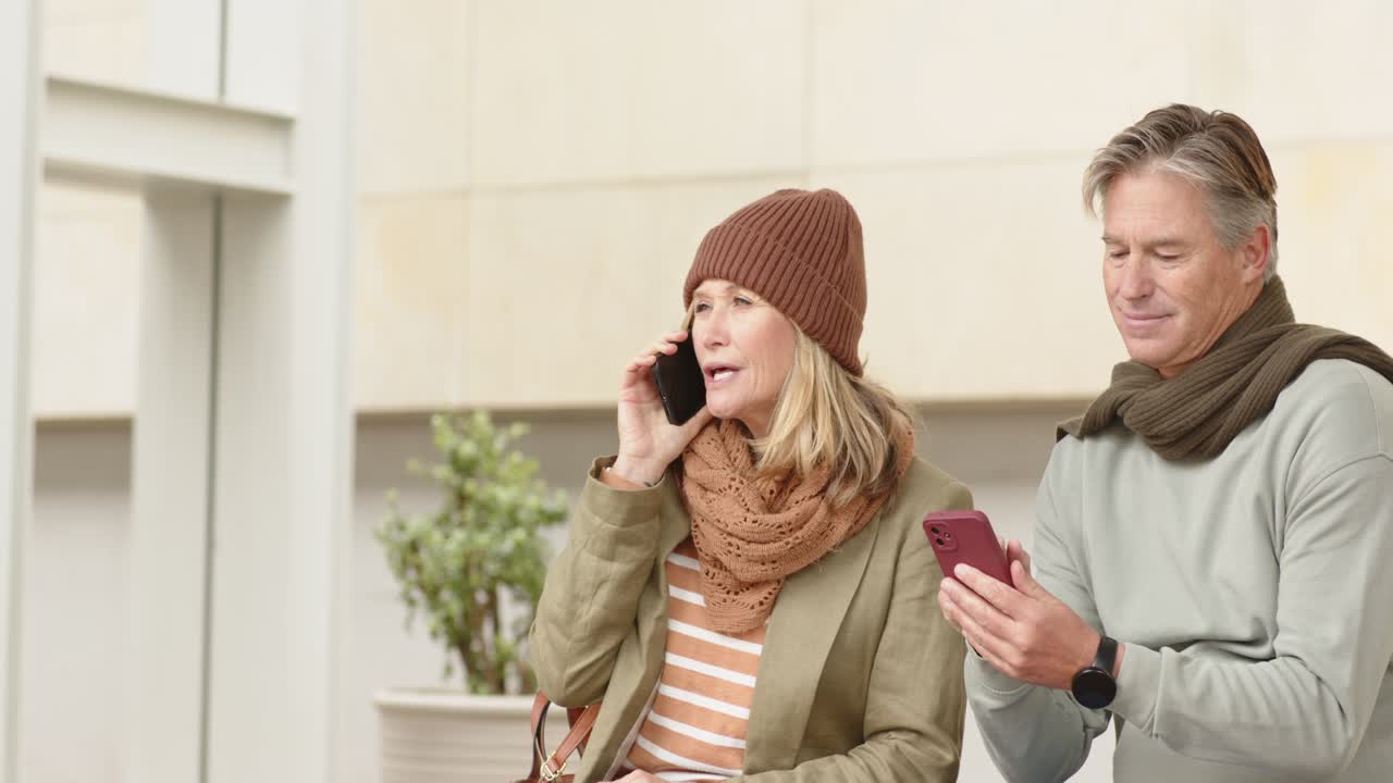 Akıllı telefonunu kulağına götüren yaşlı çift, kadın arama yapıyor, adam bankta mesajlarını kontrol ediyor