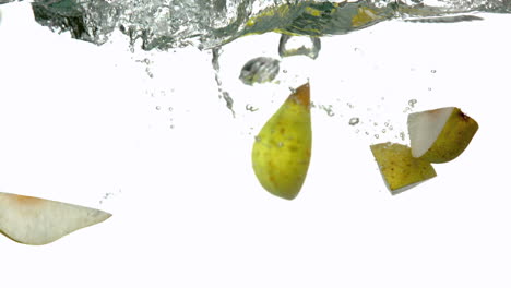 segmentos de pera sumergiéndose en el agua sobre un fondo blanco