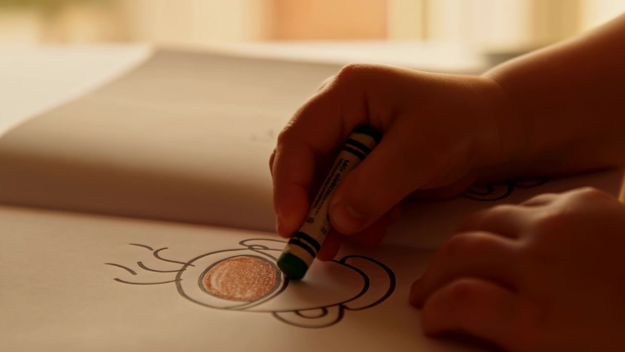 Temporal summary: creative sequence shows child's hands progressing from initial sketching to final coloring over course of clip
